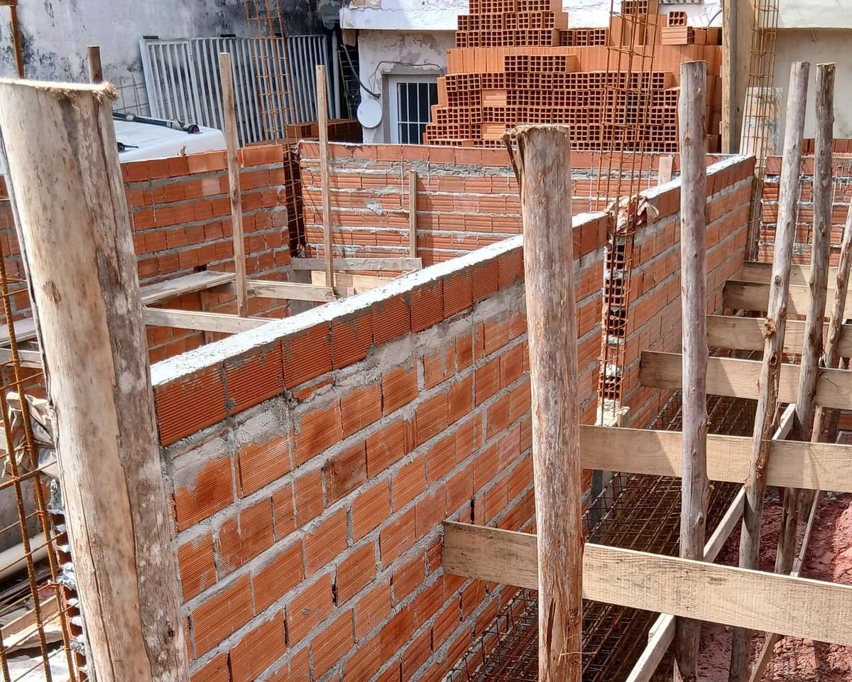 Obra residencial em alvenaria de tijolo cerâmico, com escoras de madeira e ferragem aparente