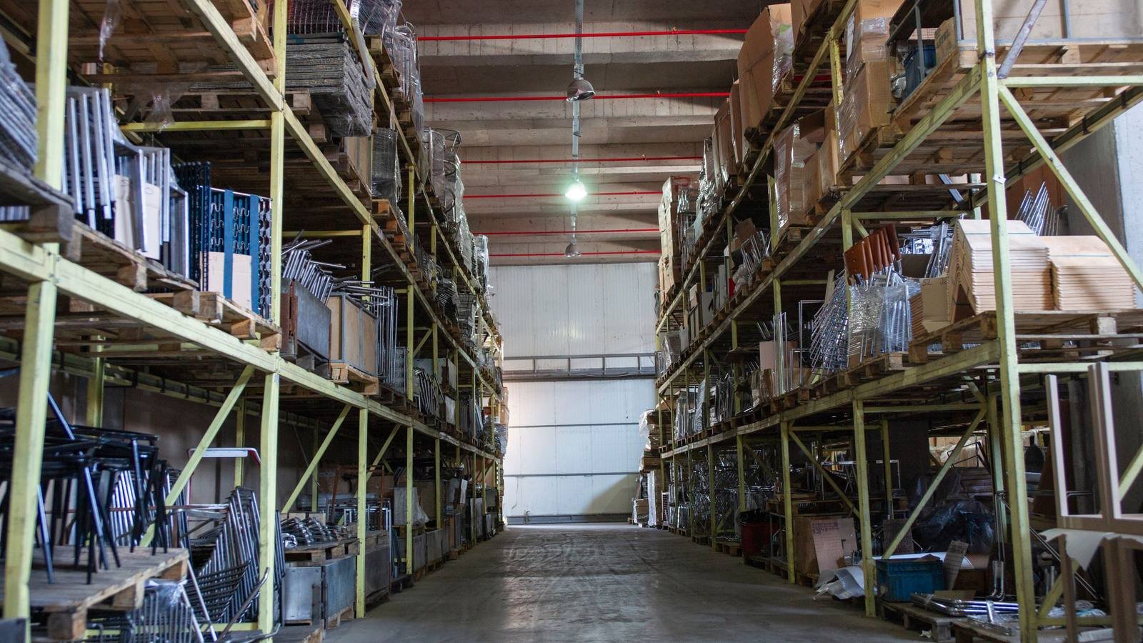 Corredor de estoque de uma empresa, com mercadoria e caixas organizadas em prateleiras industriais